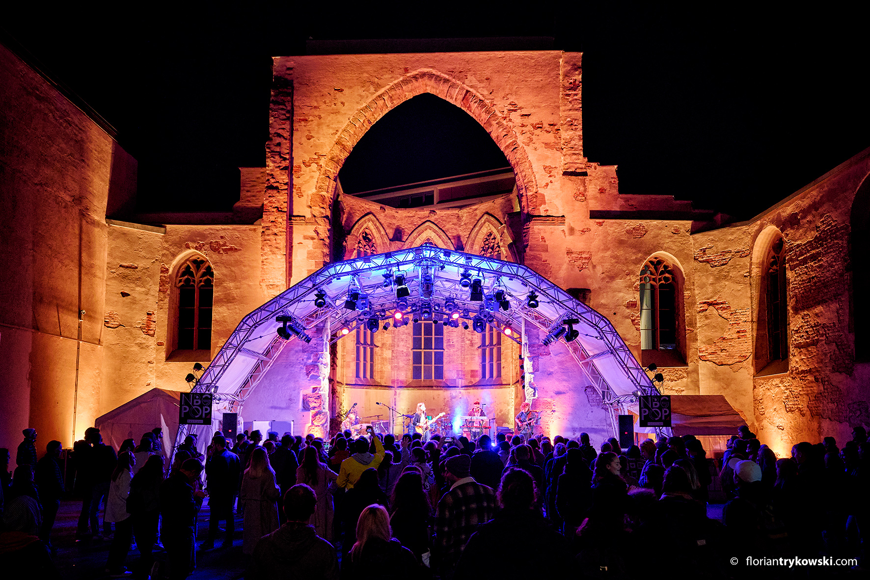 Bühne mit Beleuchtung vor einer beleuchteten gotischen Ruine und Publikum bei Nacht