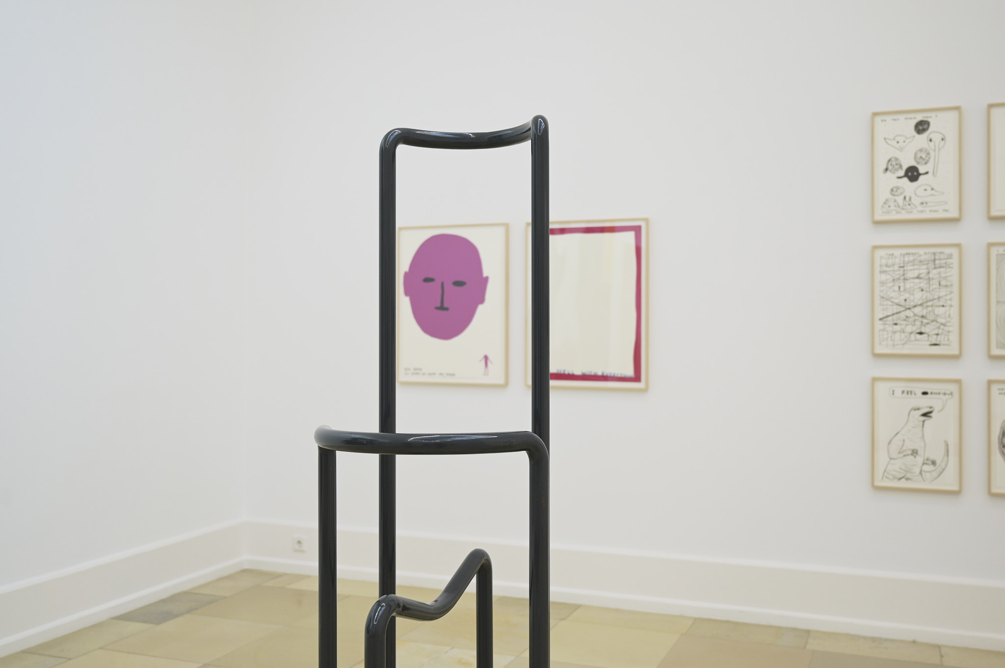 Zeichnungen von David Shrigley, davor ein Stahlgestell als Bildbetrachtungshilfe