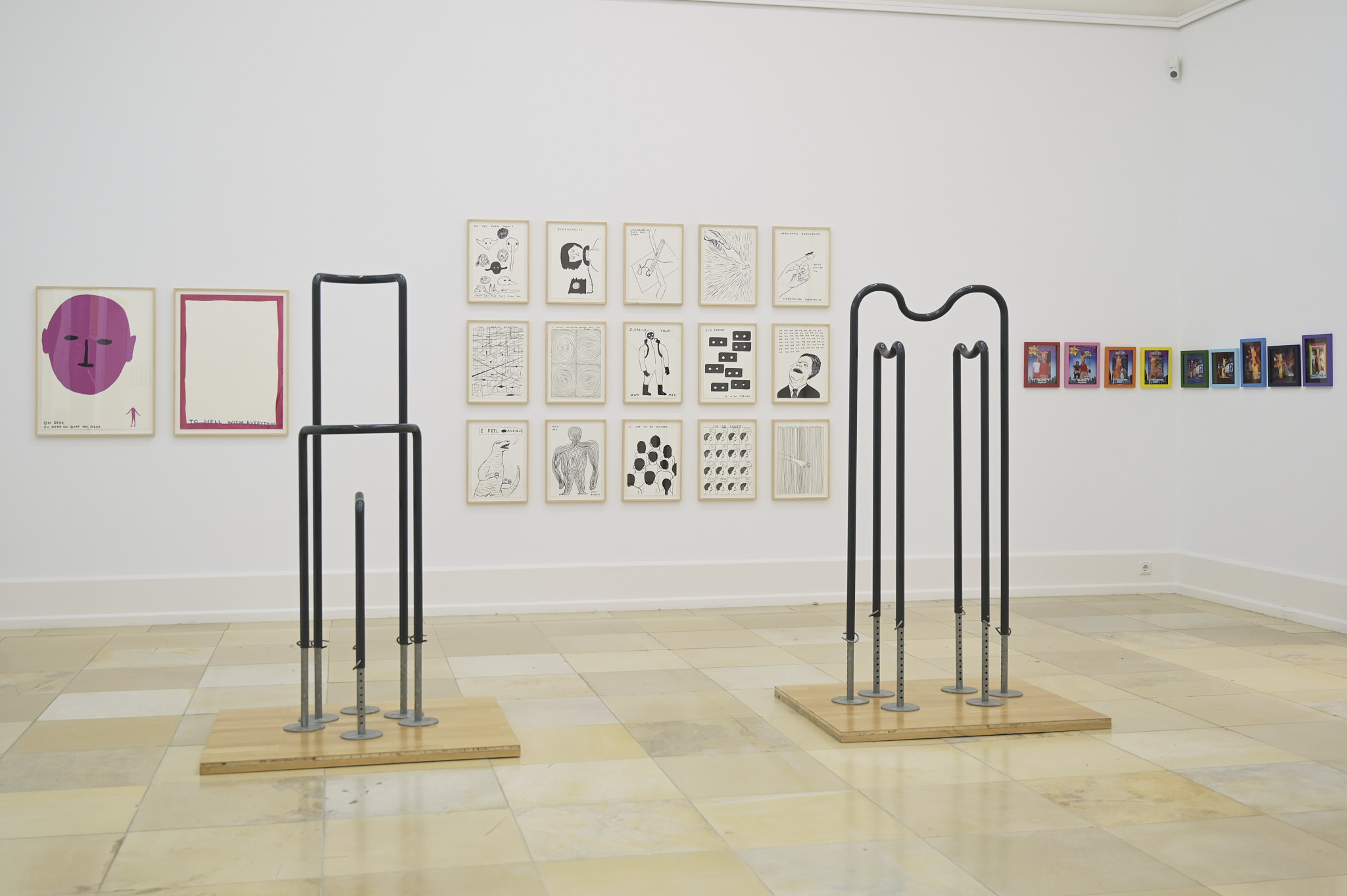 Zeichnungen von David Shrigley, davor ein Stahlgestell als Bildbetrachtungshilfe