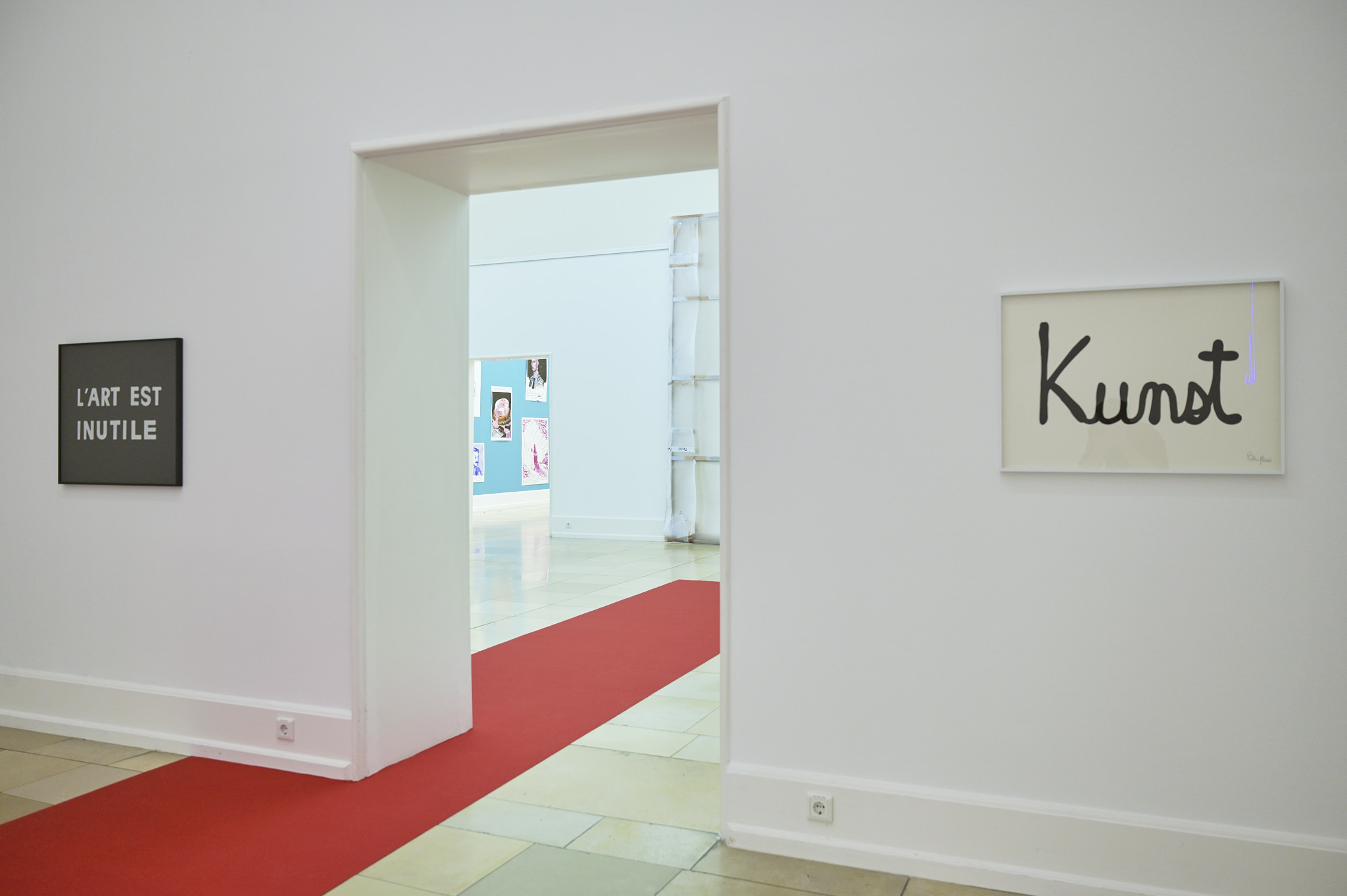 Ein Roter Teppich zieht sich vom Foyer durch zwei Ausstellungsräume der Kunsthalle, an der Wand zwei Schriftarbeiten von Ben Vautier
