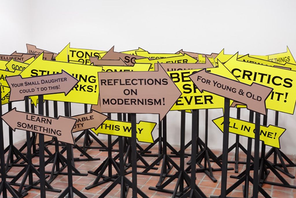 Schilderwald aus Pfeilen mit marktschreierischen Slogans zur besten Ausstellung aller Zeiten