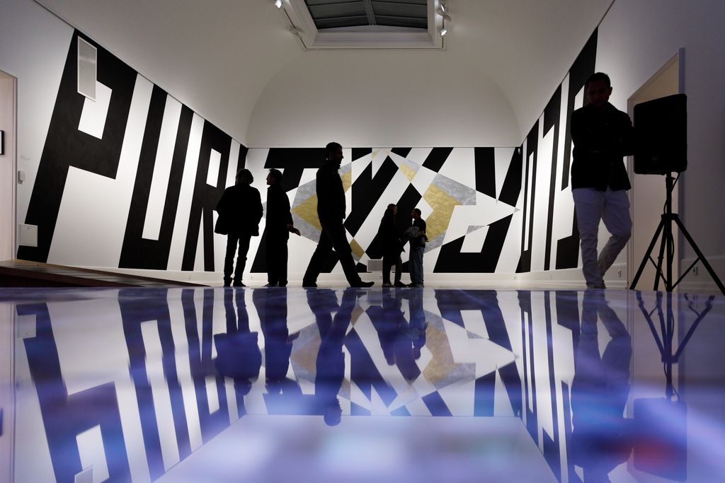 Schriftzug Purity Gloy in Schwarz wandhoch über drei Wände verteilt