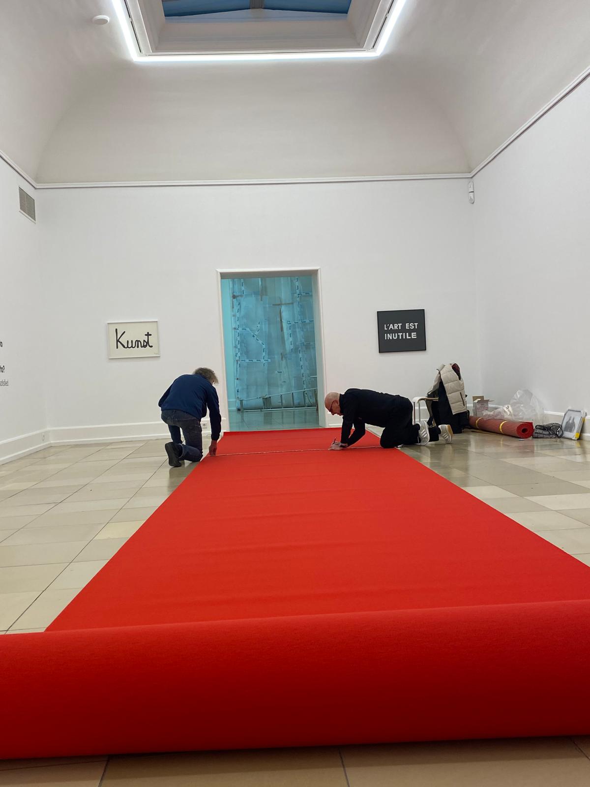 Maik und Dirk Löbbert rollen einen roten Teppich für ihre Arbeit Welcome aus