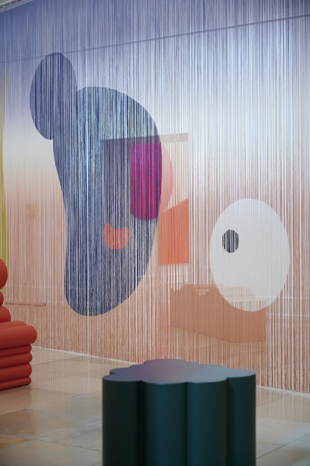 Ein Vorhang aus Fäden, bedruckt mit Fantasieformen, quer durch den Raum gespannt