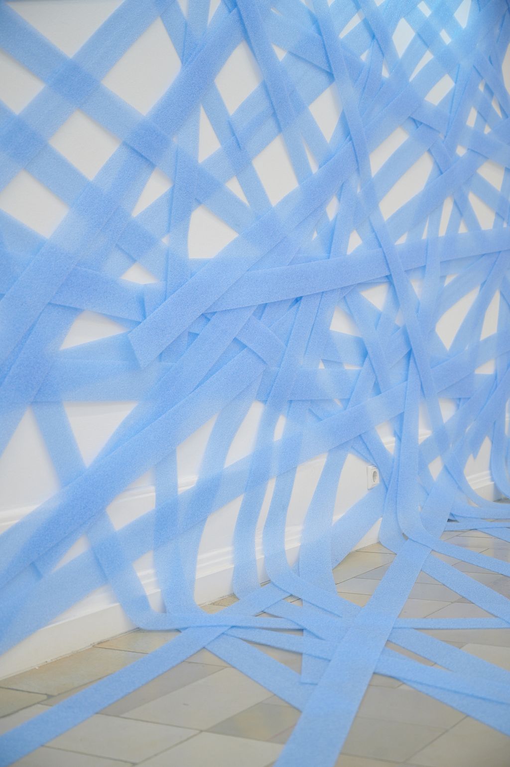 Blaue Dämmstreifen in gleicher Breite bilden ein wandfüllendes Geflecht