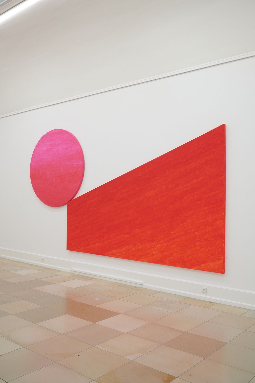 Auf eine schiefe Ebene in grellen Rottönen trifft am Ende ein großer pinkfarbener Kreis