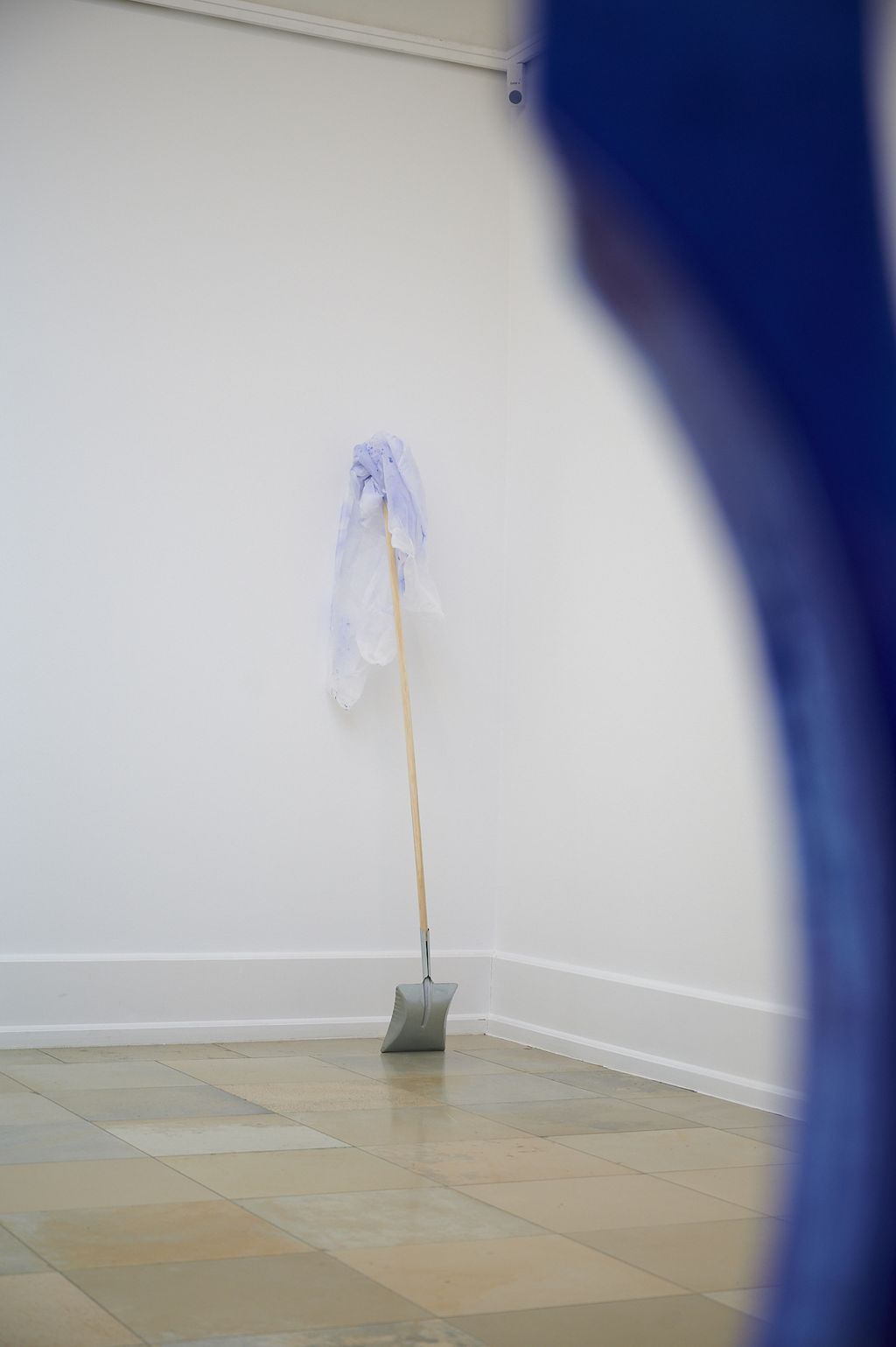 Eine Schaufel und ein benutzter blau besprühter Schutzanzug lehnen als Hinterlassenschaften einer Malaktion an der Wand