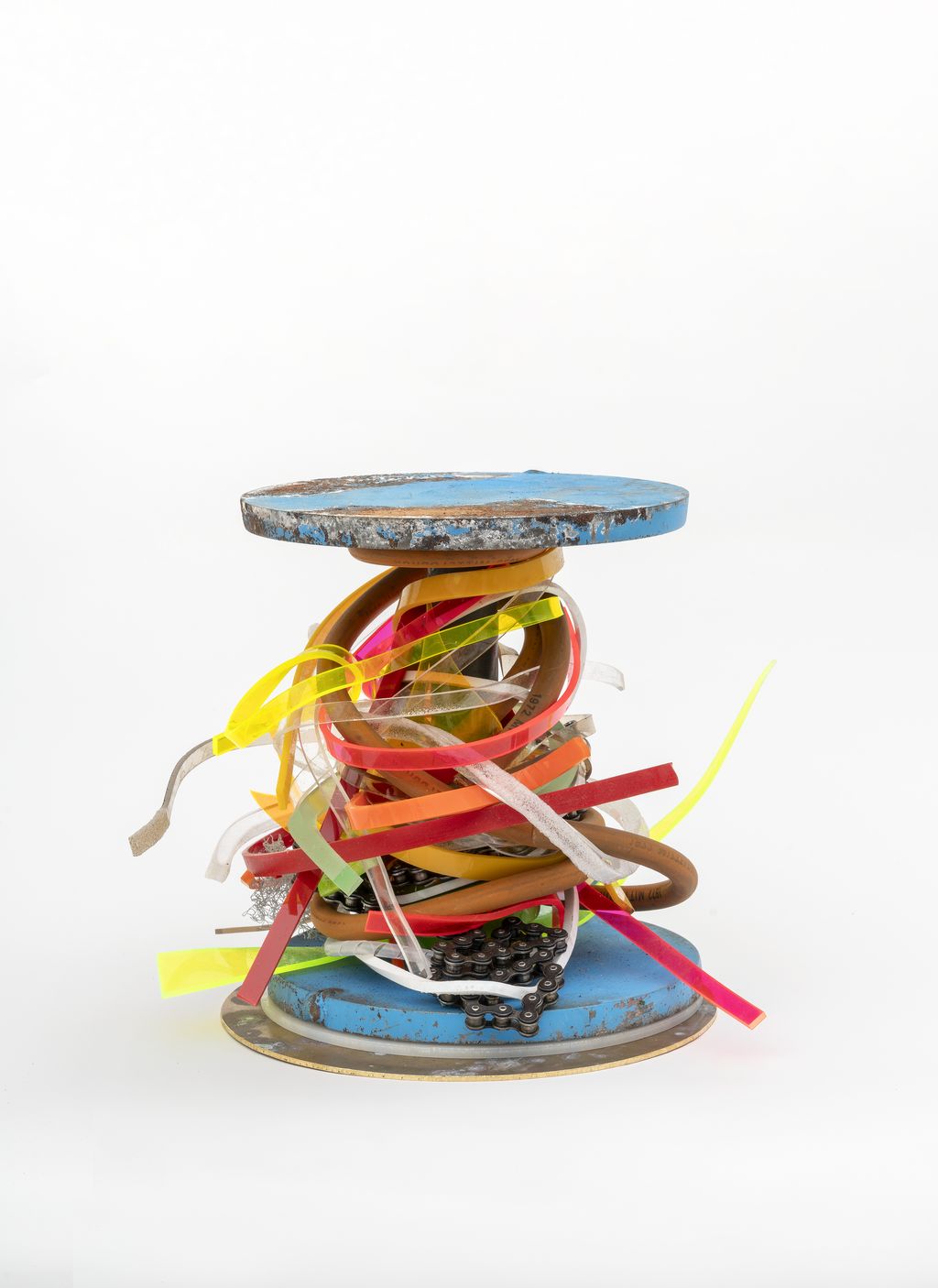 Zeitgenössischer Pokal aus zwei blauen Metallscheiben, die eine Metallstange halten. Die Stange ist umwiceklt mit farbigen Bändern und einer Maschinenkette