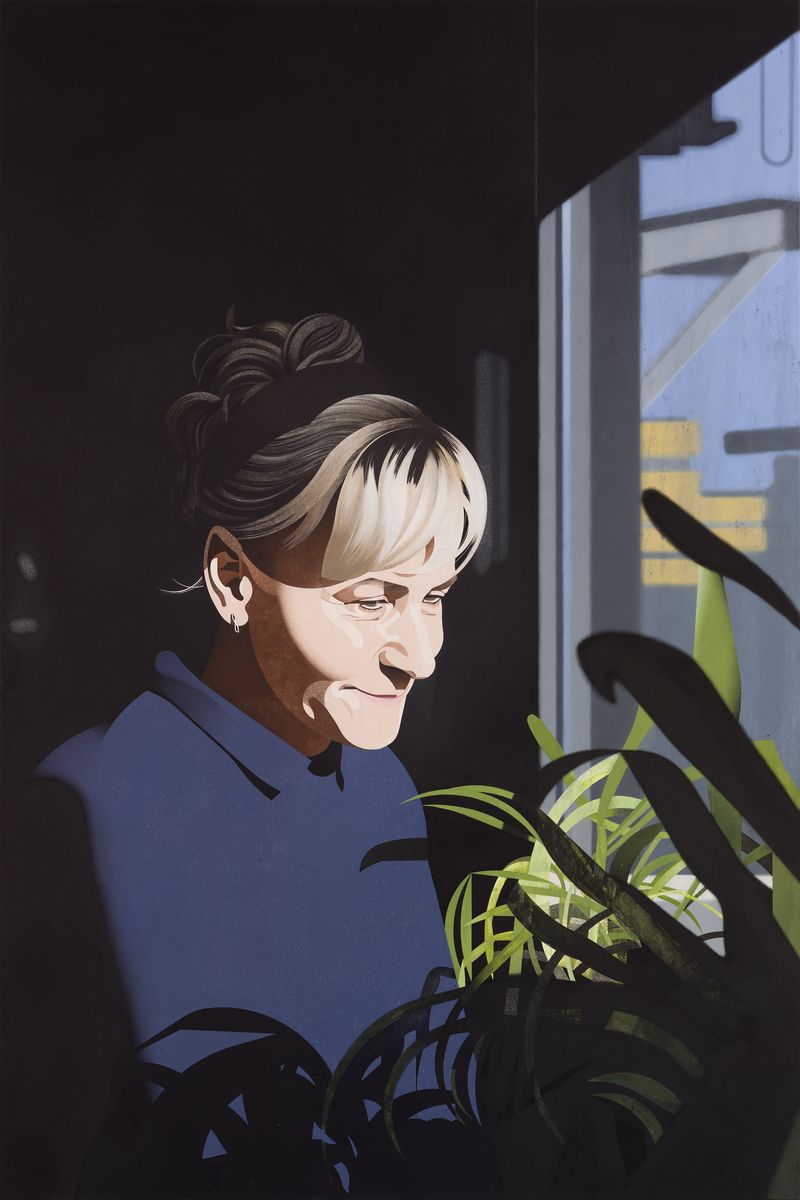 Eine blonde Frau in einem blauen Kleid steht an einem Blumenfenster, ihr Gesicht in gleißendem Sonnenlicht