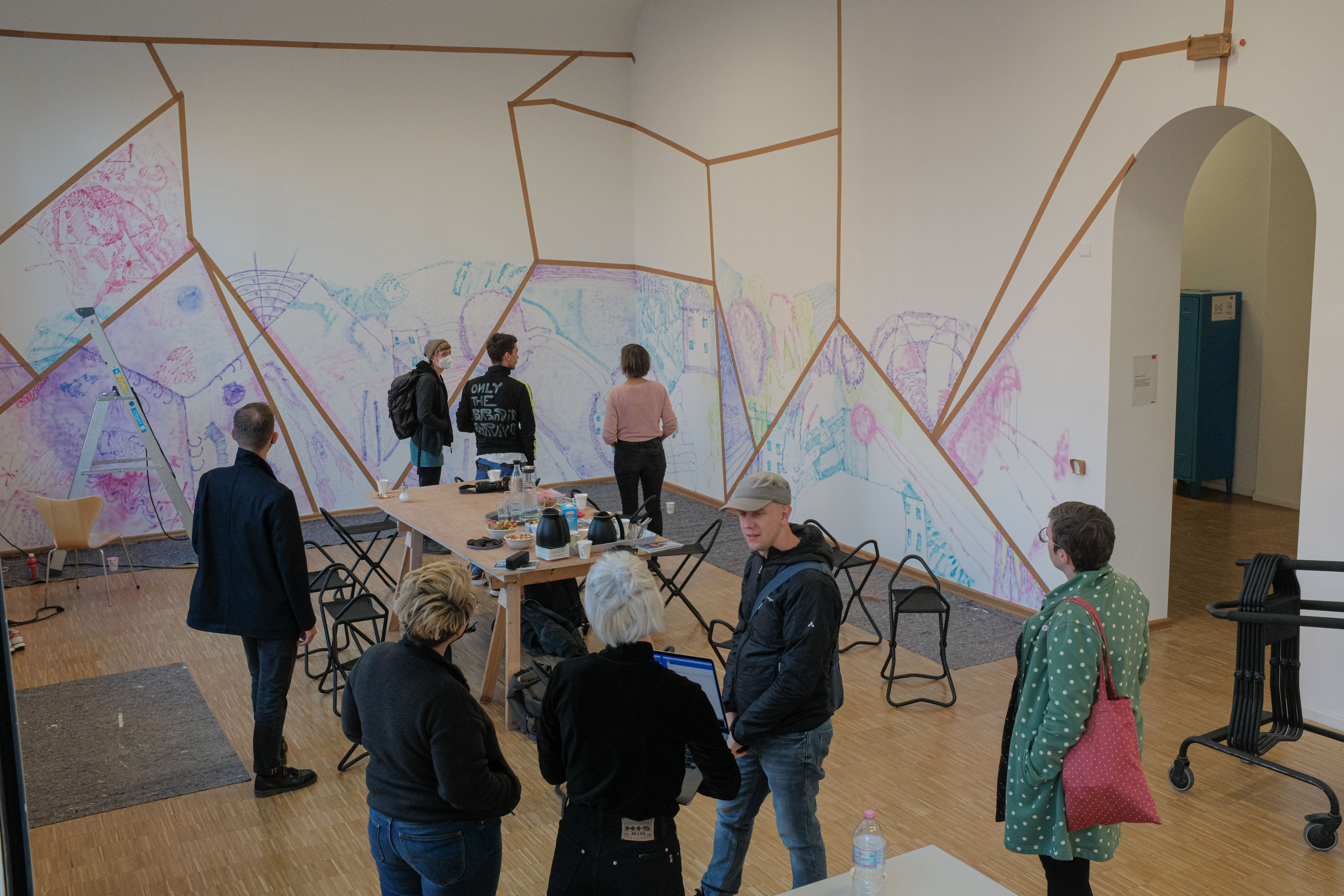 Menschen in einem Ausstellungsraum mit bunt bemalten Wänden