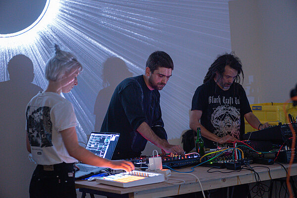 3 DJs vor einer Wandprojektion